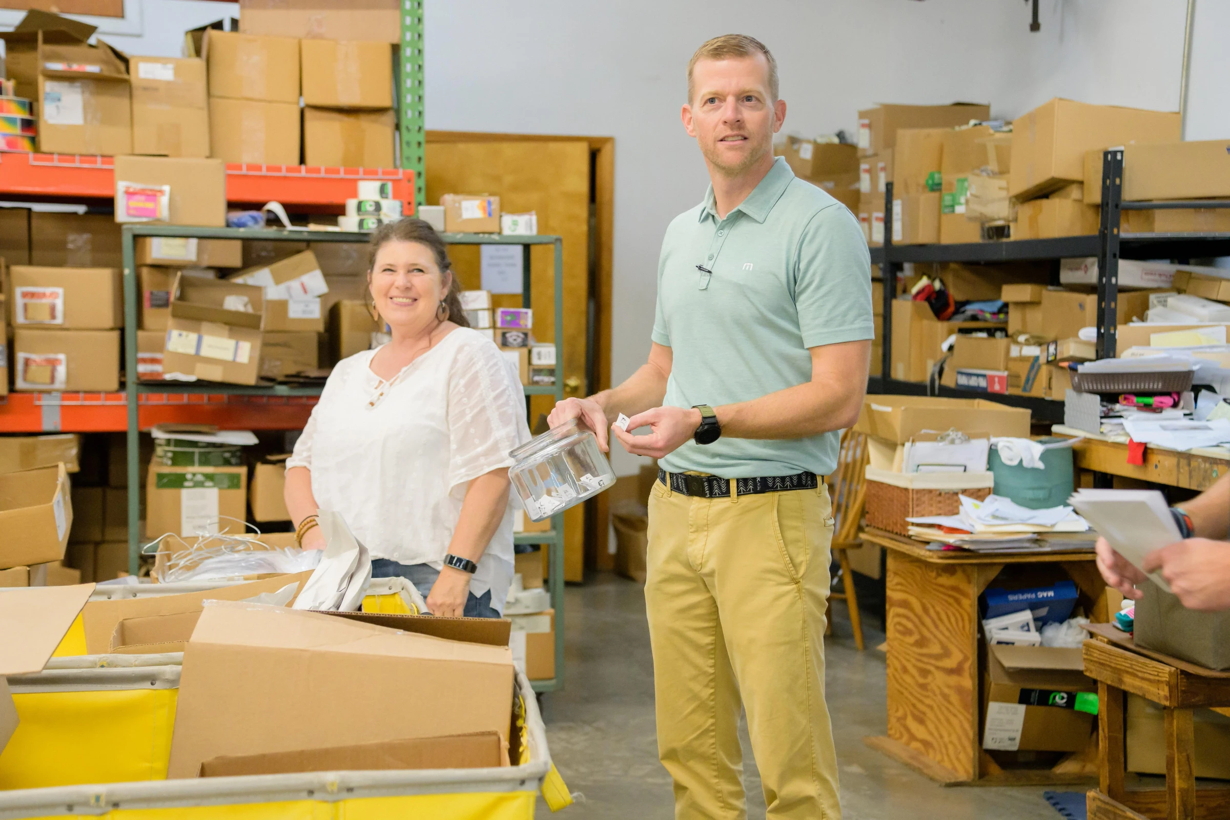 Two people talking in a warehouse stocked with boxes