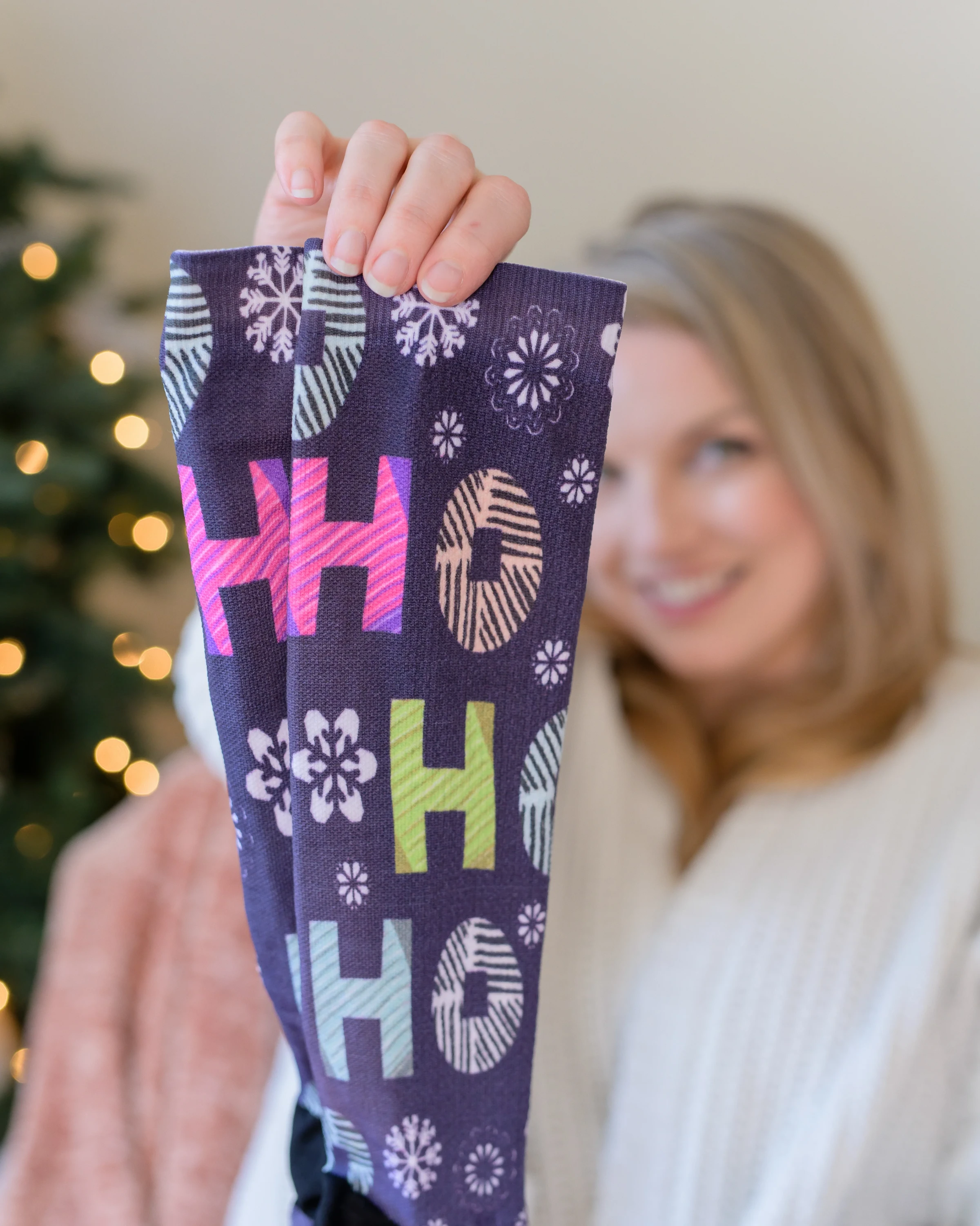Woman holding up a purple patterned sock toward the camera