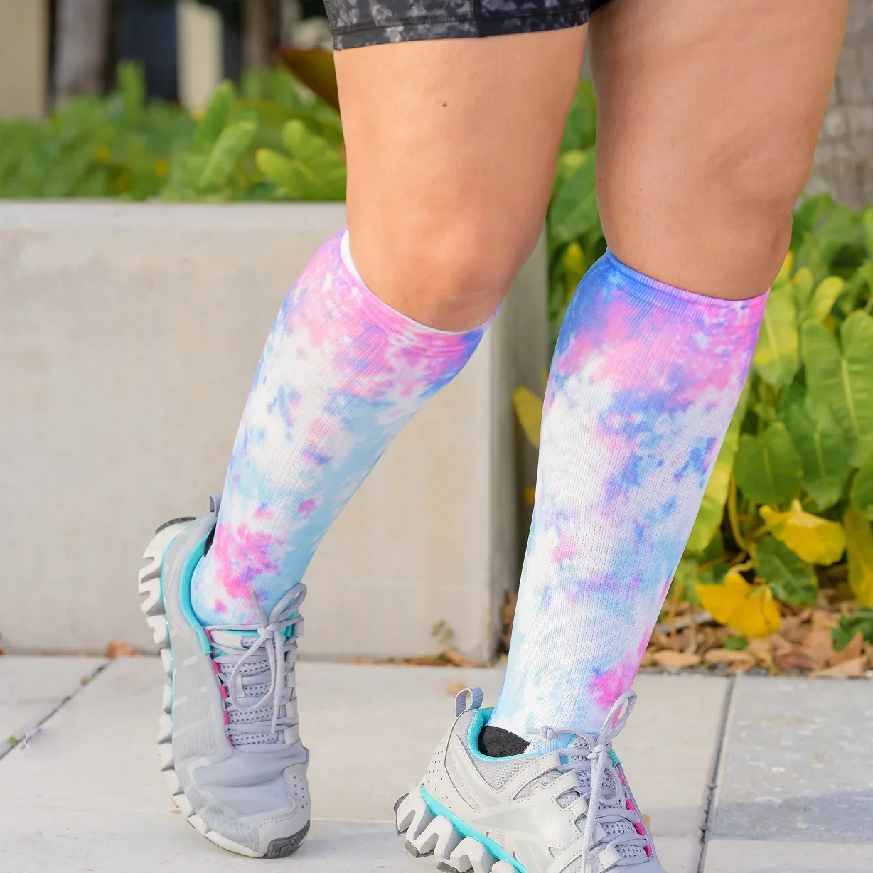 Legs in tie-dye knee-high socks and sneakers